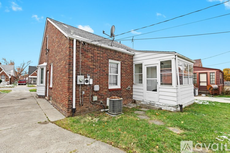 A house with a white siding and a brick chimney is for sale.