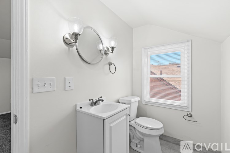 A bathroom with a toilet, sink, and light fixture.