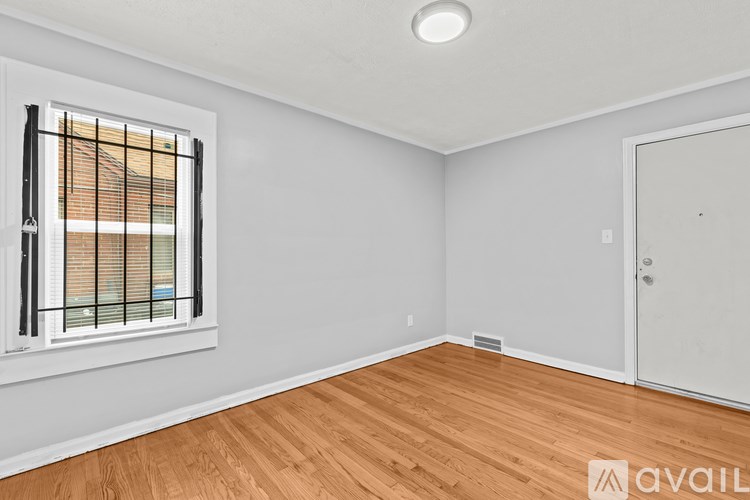 A room with wooden flooring and a window with blinds.