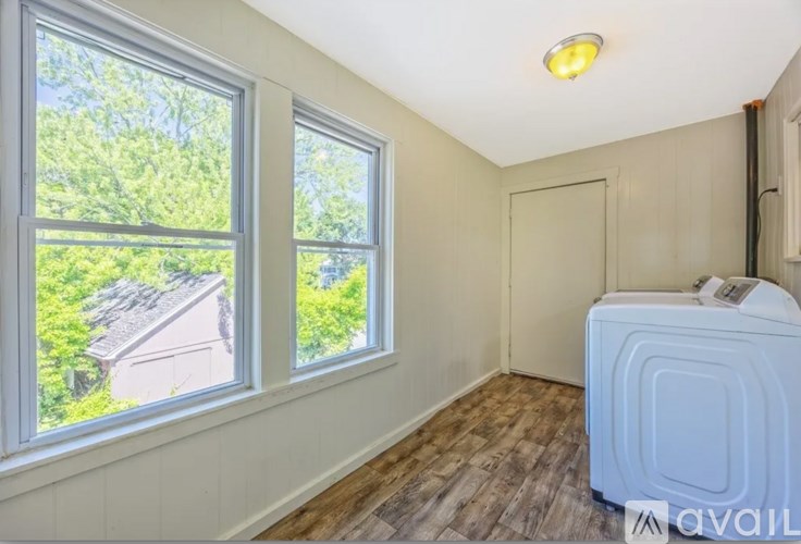 A room with a window and a washing machine.