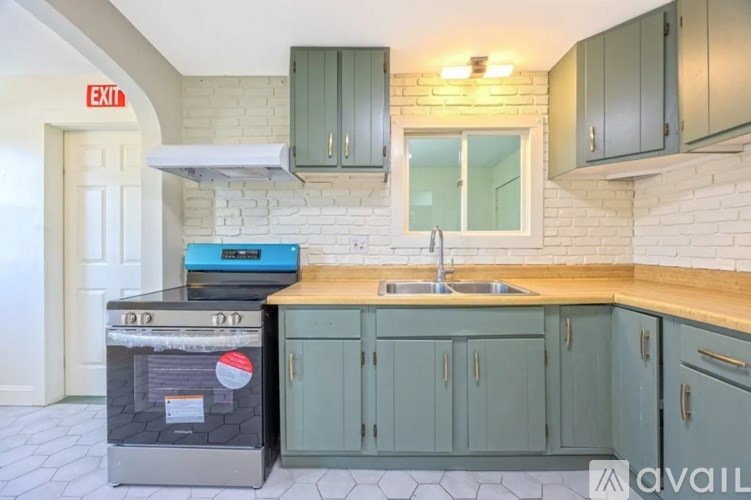 A kitchen with a stove, sink, and cabinets.
