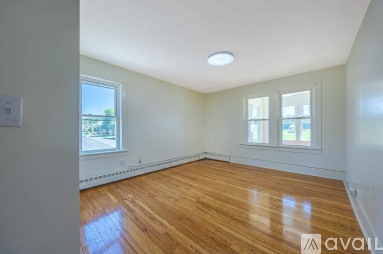 A room with wooden flooring and a window overlooking a street.