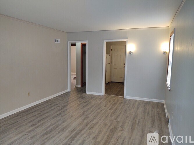 A spacious room with wood flooring and two doors.