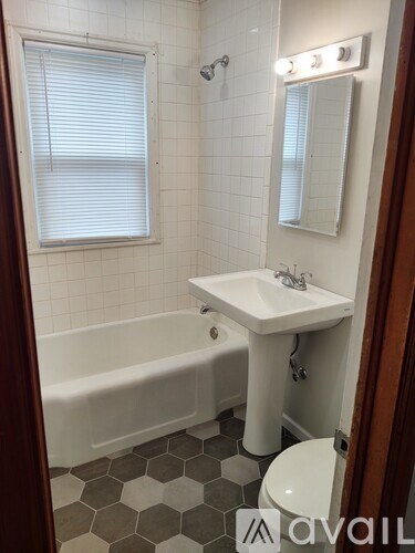 A bathroom with a white tub, sink, and hexagonal tile floor.
