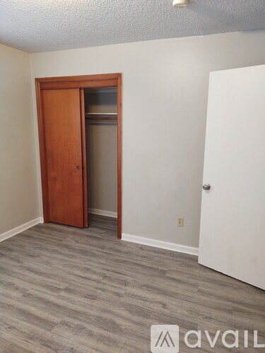 A room with a wooden door and a grey carpet.
