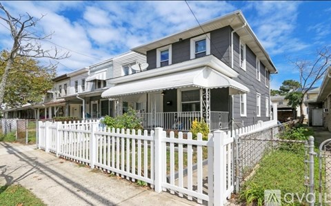 A two-story house with a white picket fence in front.