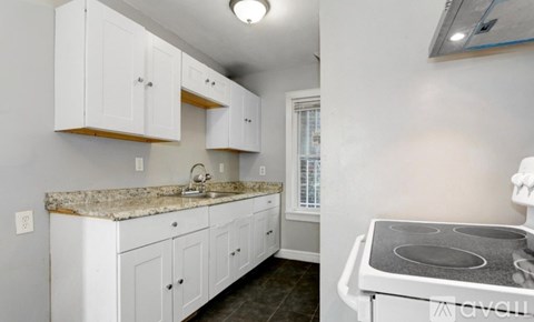 A kitchen with white cabinets and a granite countertop.