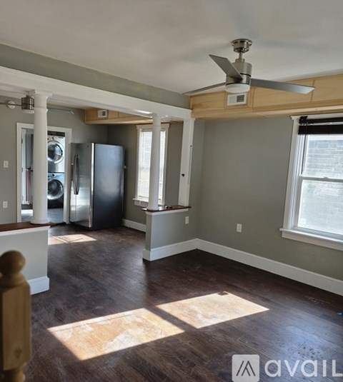 A room with a ceiling fan and a refrigerator.