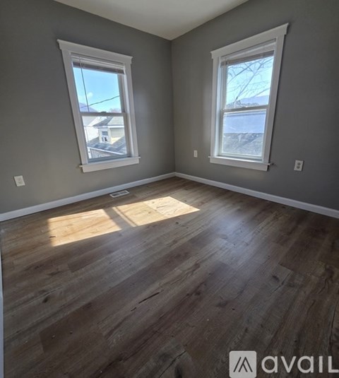 A room with wooden floors and two windows.