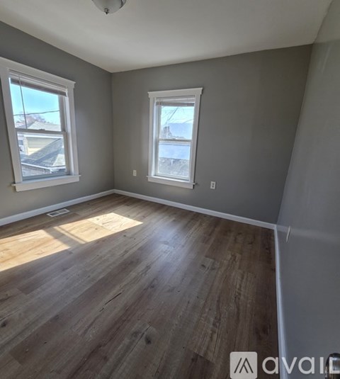 A room with wooden floors and two windows.