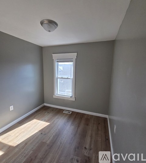 A room with a window and wooden flooring.