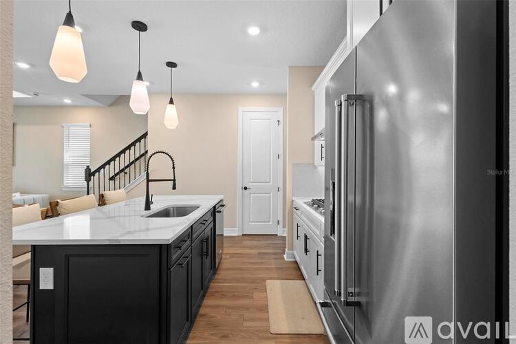 A modern kitchen with a stainless steel refrigerator and pendant lights.