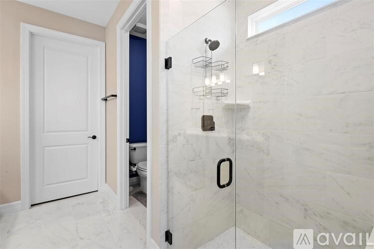A bathroom with a walk-in shower and a toilet visible in the doorway.