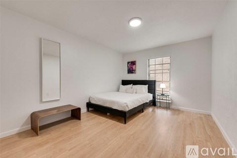 A bedroom with a bed, bench, and a mirror on the wall.