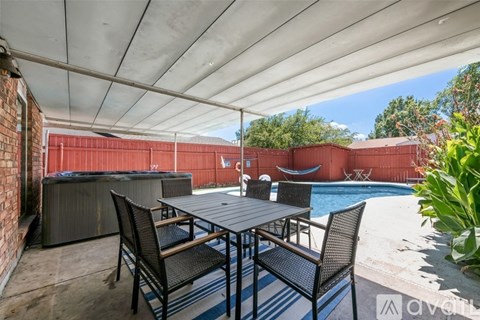 A patio with a table and chairs overlooking a pool.