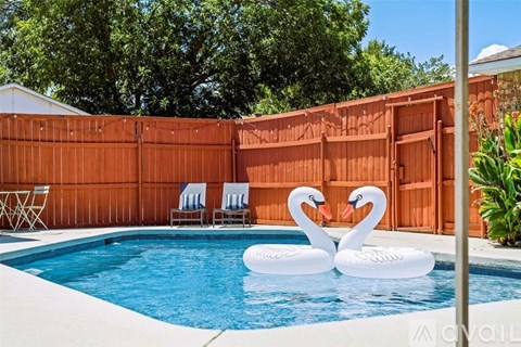 A pool with two swan floaties in the middle of it.