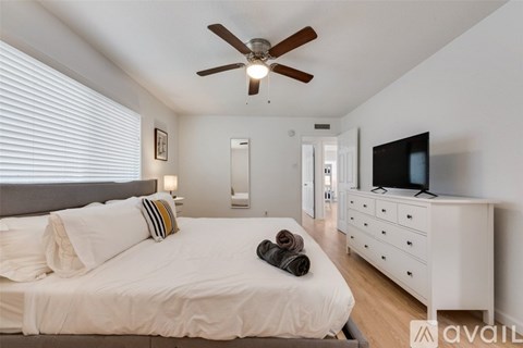 A bedroom with a bed, dresser, and television.