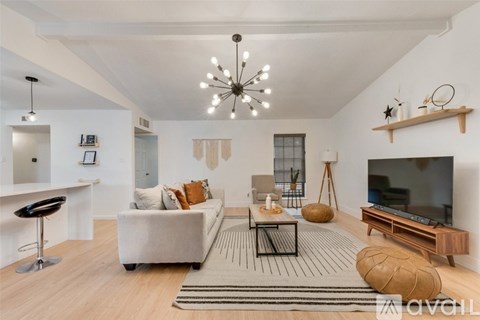 A modern living room with a white sofa, a black chair, and a wooden coffee table.