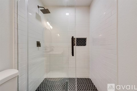 A white tiled bathroom with a glass shower door.