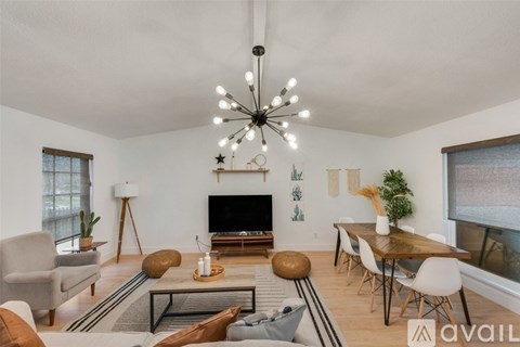 A living room with a television, a couch, a chair, a table, and a potted plant.