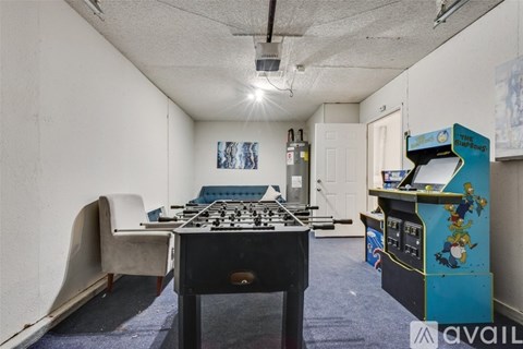 A room with a foosball table and a vintage arcade machine.