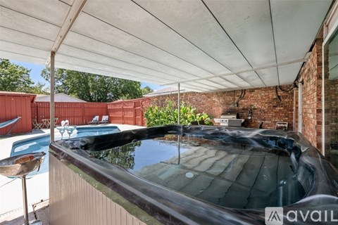 A pool under a white canopy with a brick wall in the background.