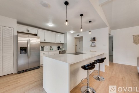 A modern kitchen with a white island and stools.