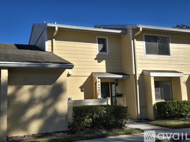 A beige house with a black roof and a white door.