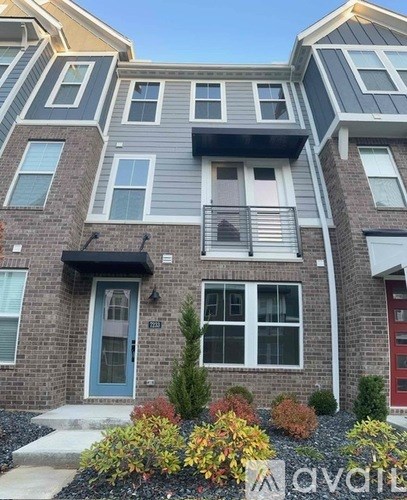 A modern two-story house with a blue door and a balcony on the second floor.