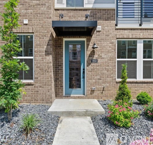 A brick house with a blue door and a small garden in front.