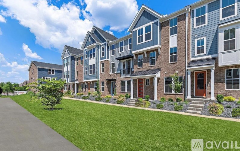 A row of modern townhouses with a grassy front yard.