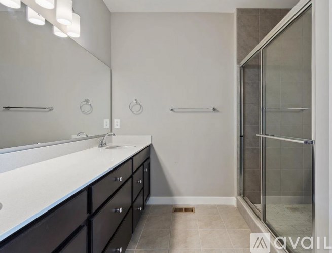 A bathroom with a sink, mirror, and shower.