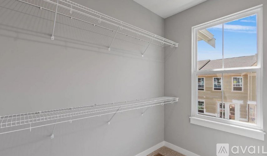 A room with a window showing a building outside and empty shelves on the wall.