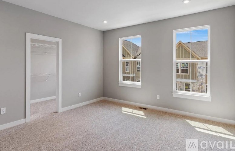 A spacious room with a carpeted floor and two windows.