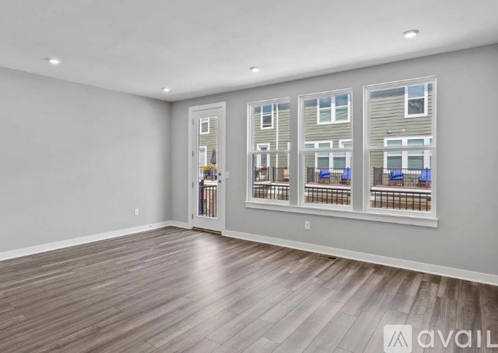 A spacious room with wooden flooring and a wall of windows.