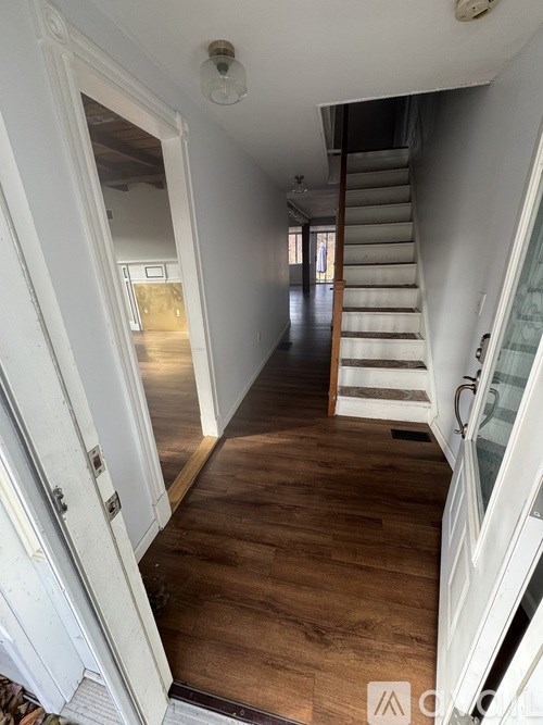 A hallway with a staircase and a door on the left.