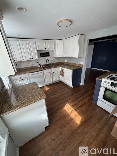 A kitchen with white cabinets and a wooden floor.