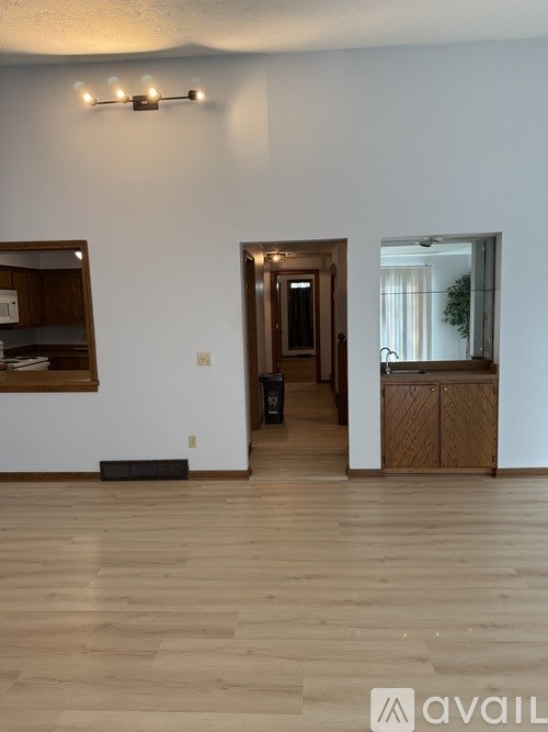 A room with wooden floors and a doorway leading to another room.