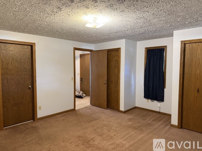 A room with a carpeted floor and four doors.