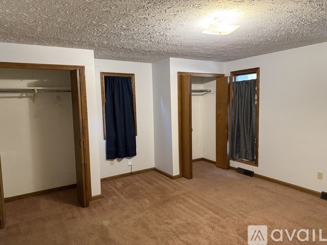 A room with a carpeted floor and a couple of closets.