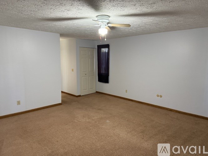 A room with a carpeted floor and a ceiling fan with a light.