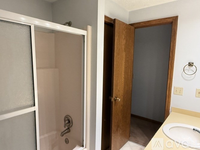 A white door with a glass panel and a silver handle is open to a dark room.