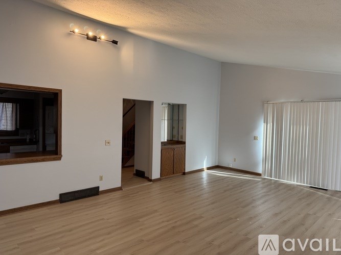 A spacious room with wooden flooring and a large window.