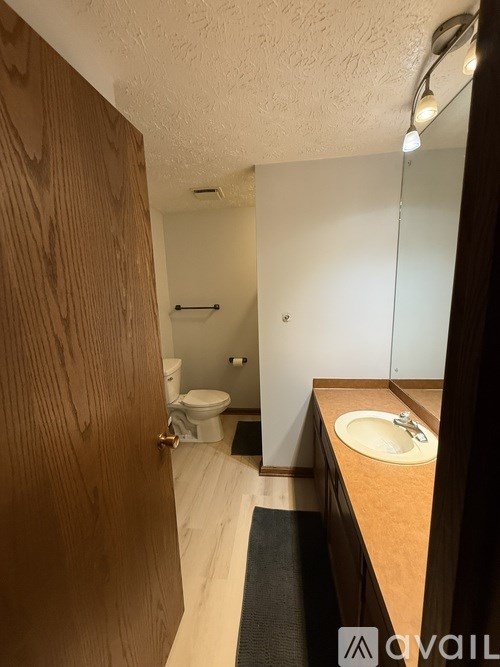 A bathroom with a toilet, sink, and mirror.