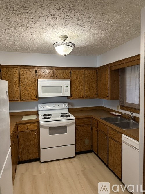A kitchen with wooden cabinets and white appliances.