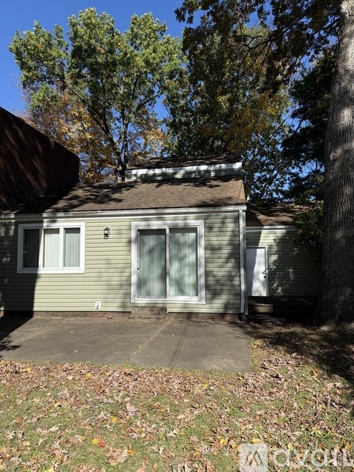 A house with a brown roof and a grey wall with a white door and window.