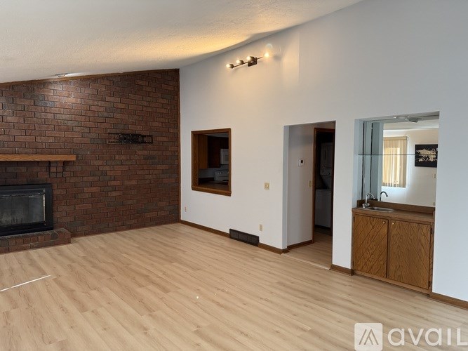 A living room with a brick fireplace and wooden floors.