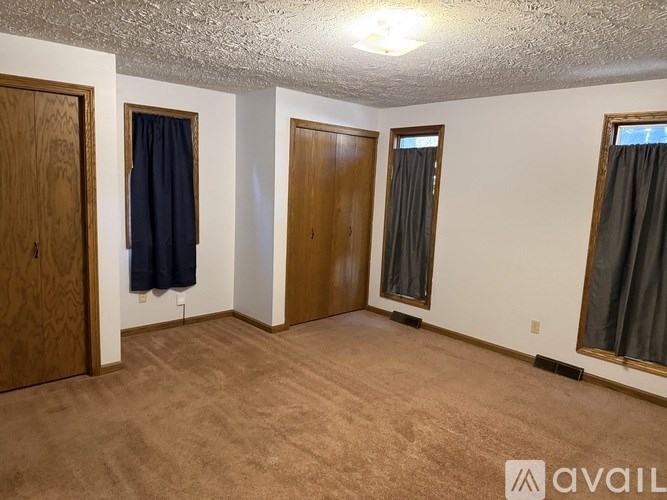 A room with brown carpet and three doors.