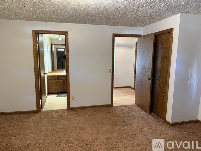 A room with a carpeted floor and two doors, one of which is open.