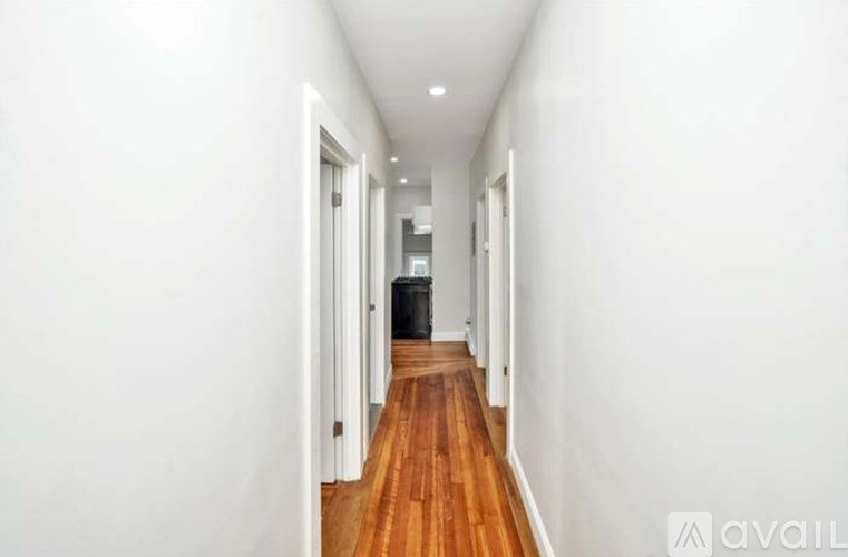 A long hallway with wood floors and white walls.
